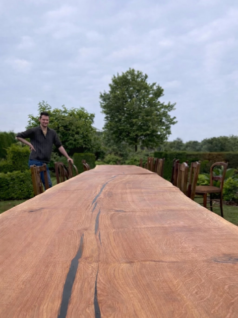 Lange massieve eiken boomstamtafel opgesteld in tuin voor event